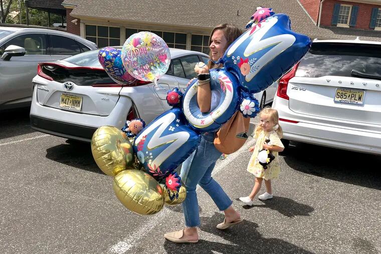 May 9, 2022: Stephanie Carol carries Mother’s Day balloons to her car in the Haddonfield Acme parking lot last week, with her 3-year-old daughter, Reilly, at her side. She bought the inflatables for her mother.