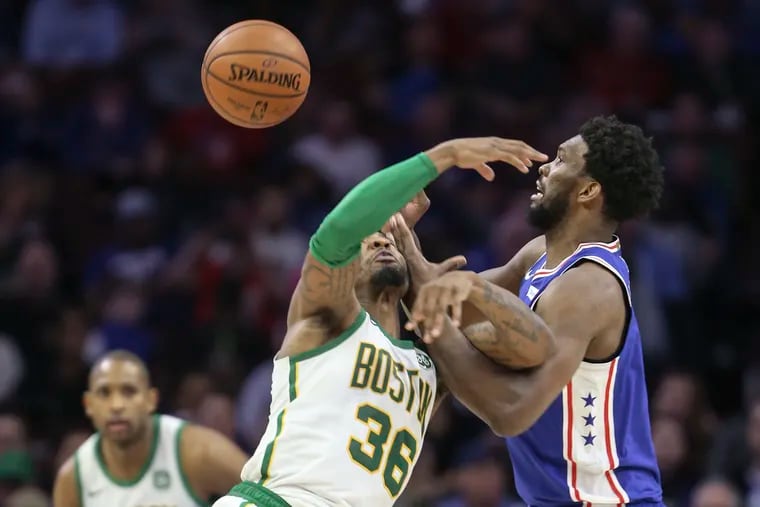 Sixers' Joel Embiid tries for the loose ball with Celtics' Marcus Smart during the third quarter at the Wells Fargo Center on Wednesday night.