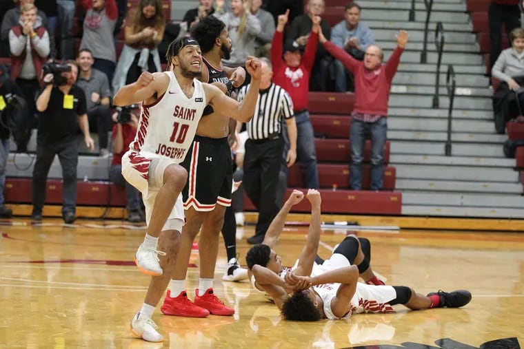 Troy Holston, left, of St. Joseph’s celebrates after their 61-60 victory over Davidson on Jan. 15, 2019. 