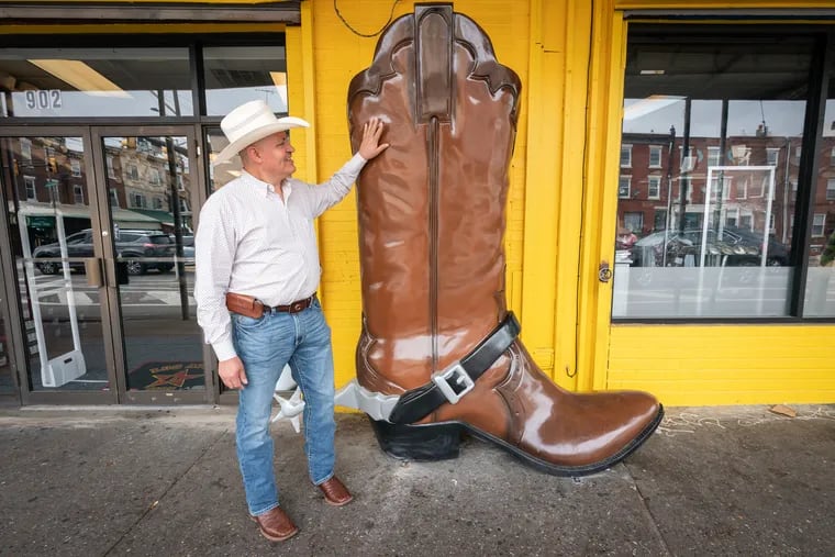 Alfonso Aramburo admires the 8-foot cowboy boot outside of his store, Viejo Oeste #2, in South Philly.