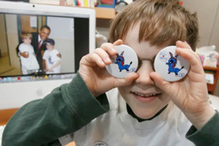 Simon Shankweiler, 8, with a photo of himself, his brother Henry and Barack Obama on the computer screen at his Swarthmore home, models buttons of the famous donkey he did for the campaign.