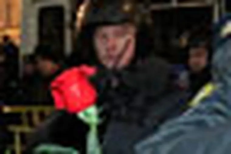 A woman tries to present a scarlet rose to a police officer during protests against alleged vote rigging in Russia's parliamentary elections in Triumphal Square in Moscow, Russia, Wednesday, Dec. 7, 2011. Protesters energized by the declining electoral fortunes of Russia's ruling party try for a third straight night of demonstrations in Moscow, facing off against a heavy police contingent.(AP Photo/Ivan Sekretarev)
