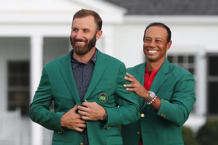 Tiger Woods, the 2019 winner, presents Dustin Johnson with his 2020 green jacket. Woods will miss his fourth Masters in eight years as he convalesces  at home in Florida from his February car crash in California.