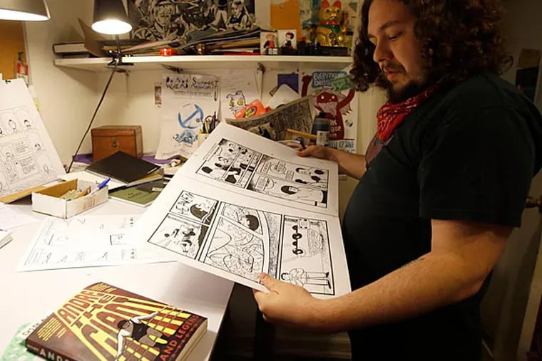 Box Brown looking at original art work from his Andre the Giant: Life
and Legend book in his West Philadelphia apartment office.  (Yong Kim/Staff Photographer)