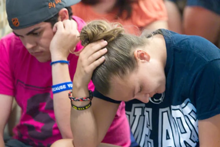 Andrew Hanselman, left, of Newtown, Pa., and Maddy Prior, of Neptune, N.J., react to the sanctions placed on Penn State. (Ed Hille / Staff Photographer)