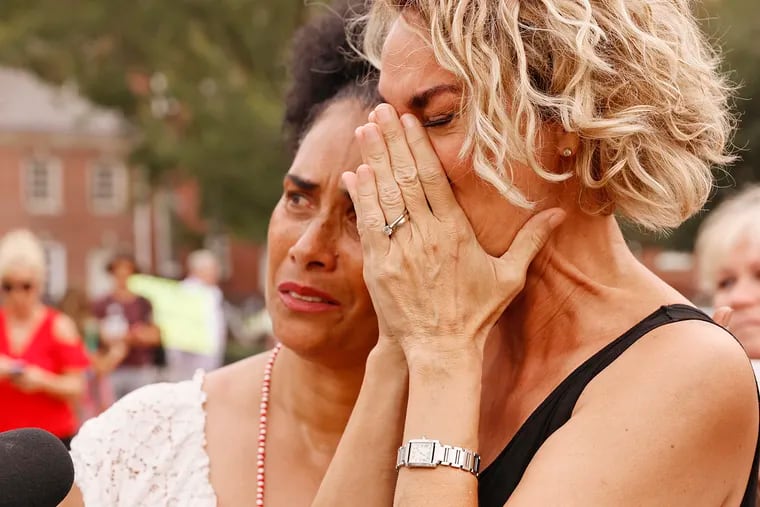 Lili Bernard (white dress) holds Stacey Pinkerton, who becomes emotional while being interviewed at the vigil at Independence Hall. Both women say Bill Cosby raped them in the mid-1980s.