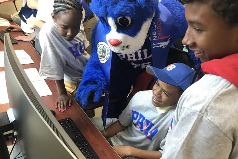 Children and the 76ers mascot check out the computers at the new education center in Camden that the team funded.