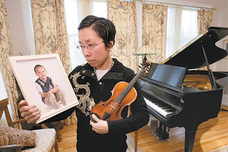 Chanlan Lee of Gladwyne was a standout violinist at the Nelly Berman Music School in Haverford. But Chanlan's musical voice is stilled. He died of viral encephalitis Dec. 19 after a month-long coma. His mother Catherine Lee holds a photo of Chanlan and his violin. (Charles Fox / Staff Photographer)