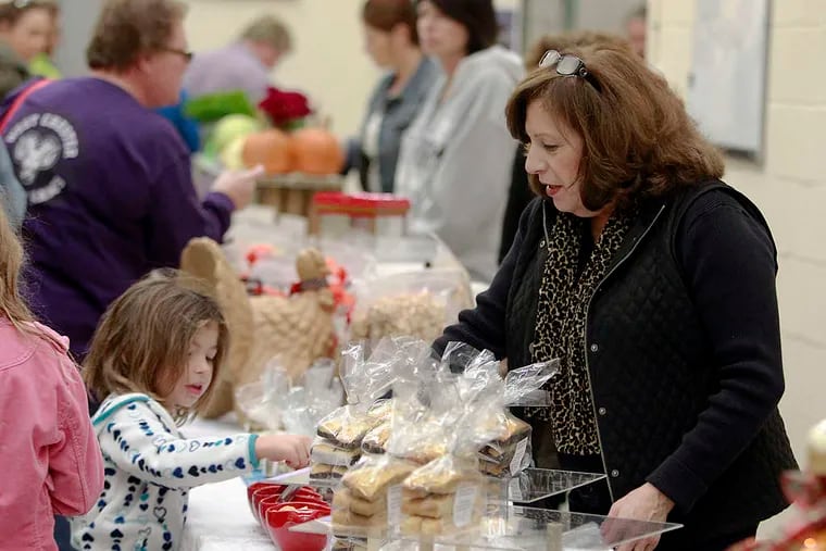 Meghan Collison, 4, picks some sample cookies from Joyce Lattuca at the Lavinia's Cookies table at the Artisan Exchange market.