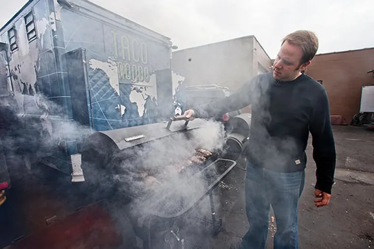 Michael Sultan, chef/owner of Taco Mondo and Street Food Philly trucks, checks on chicken in a smoker behind the Taco Mondo truck parked at the Bridesburg Commissary, Philadelphia, January 19, 2014.  ( DAVID M WARREN / Staff Photographer )