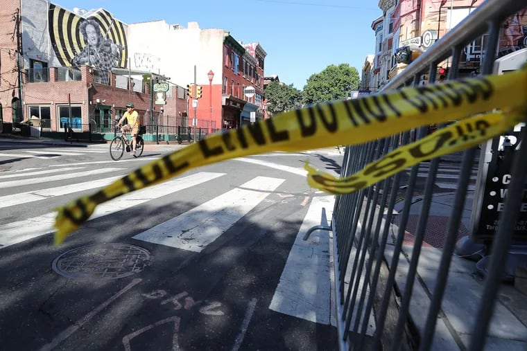 Police tape hangs from a barricade at Third and South Streets in Philadelphia on Sunday, the morning after three people were killed and 11 others wounded in  a mass shooting.