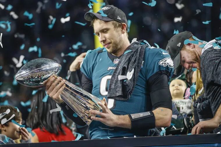 Eagle quarterback Nick Foles, left, takes a long look at the Lombardi Trophy on the victory stand as Carson Wentz, right, takes in the moment at the Super Bowl.