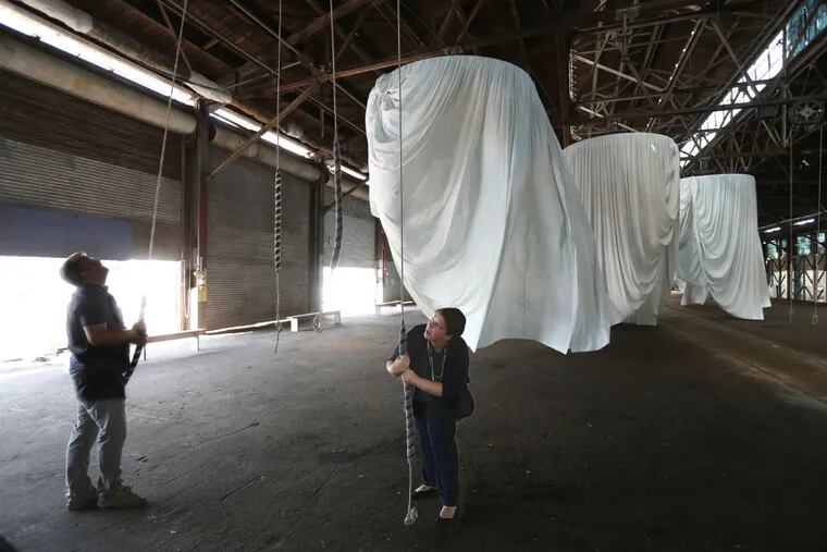 Tommy Wison (left) and Stephanie Greene pull on the ropes to make one of the 12 large circular curtains spin, as if the wind currents were making it move in the art installation habitus.