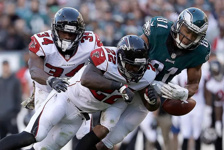Jordan Matthews drops the football after getting hit by Falcons' strong safety Keanu Neal (center).
