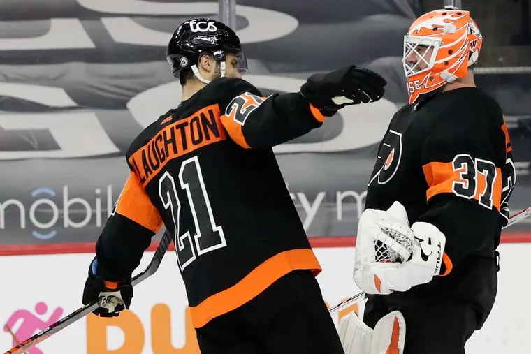 Flyers goaltender Brian Elliott and center Scott Laughton celebrate their 4-3 shootout win over the Devils.