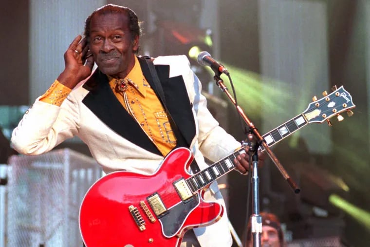 Chuck Berry listens for the crowd to sing with him during a performance of his hit song "Johnny B. Goode" at a 1995 Hall of Fame concert in Cleveland.
