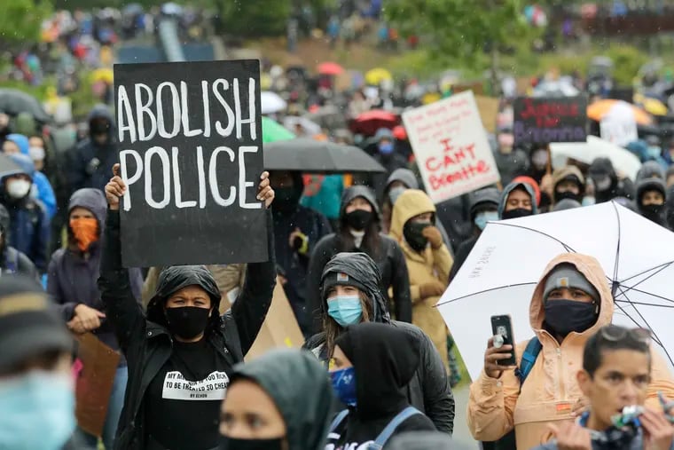 A protester holds a sign that reads "Abolish Police" during a "Silent March" against racial inequality and police brutality that was organized by Black Lives Matter Seattle-King County, Friday, June 12, 2020, in Seattle. Hundreds of people marched for nearly two miles to support Black lives, oppose racism and to call for police reforms among other issues.