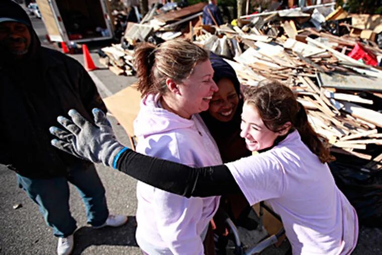 In Atlantic City, Gloria Woody (center), 72, gets a hug from Cindy Rodgers (left) and Jenna Tibbitts, both volunteers from First United Methodist Church in Moorestown. "It’s like God sent me angels to help fix this," Woody said. At left is her son Frank, 48. DAVID SWANSON / Staff Photographer