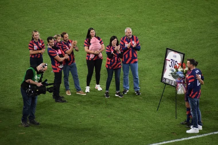 Carli Lloyd (second from right) stands with her husband Brian Hollins (right) across from members of Lloyd's family including her father Steve (right) and mother Pamela (second from right) during a pregame ceremony at Lloyd's last U.S. national team game. Lloyd was presented with a jersey bearing her name and the message "316 Caps," representing the number of national team games she played in her career.