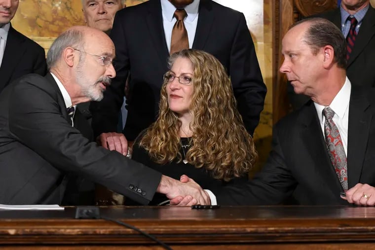 Gov. Tom Wolf shakes hands with Jim Piazza after signing anti-hazing legislation inspired by Piazza's son, Penn State student Tim Piazza, who died after a night of drinking in a fraternity house, Friday, Oct. 19, 2018, in Harrisburg, Pa. Sitting between them is Evelyn Piazza, the mother of Tim Piazza.