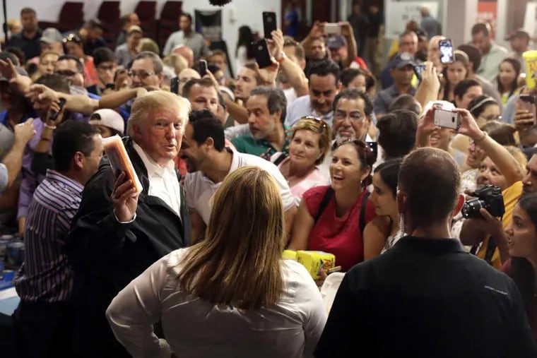President Trump gives food to a crowd affected by Hurricane Maria as he visits a disaster relief distribution center at Calgary Chapel in San Juan, Puerto Rico, on Tuesday.