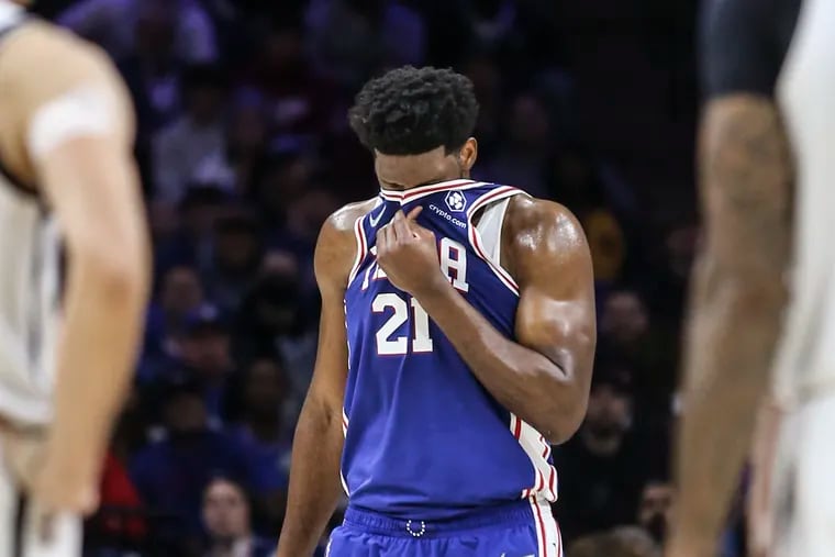 Sixers Joel Embiid wipes his face after colliding with the Nets' Nic Claxton at the Wells Fargo Center.