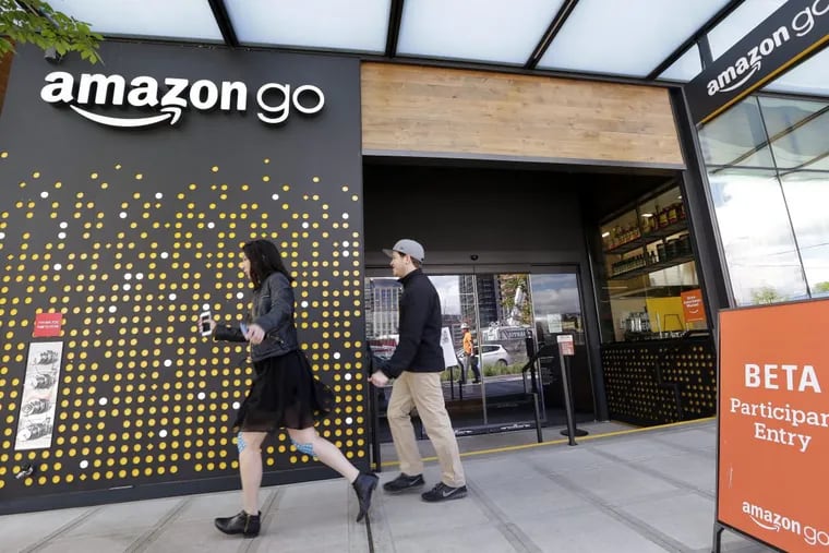 People walk past an Amazon Go store in Seattle. More than a year after it introduced the concept, Amazon is opening its artificial intelligence-powered Amazon Go store in downtown Seattle on Monday, Jan. 22, 2018.