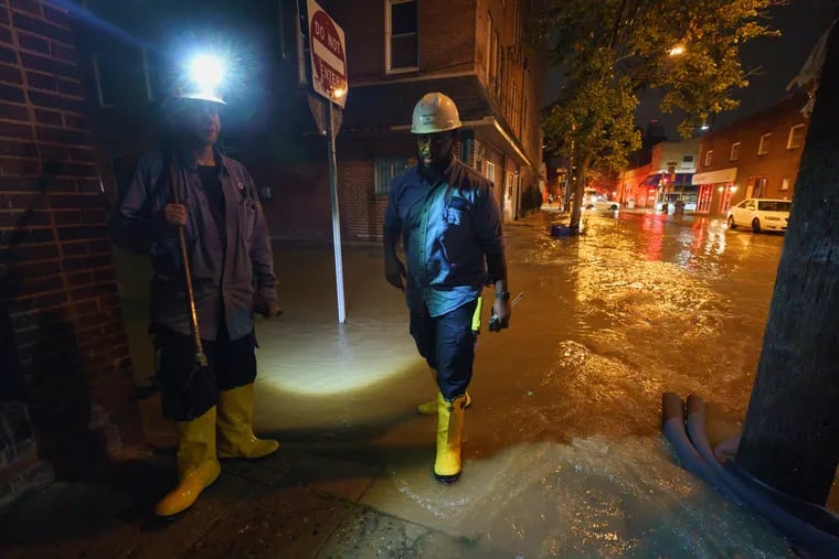 PGW employees at work at on a flooded street from a water main break on 6th Street near Bainbridge Street, in Philadelphia, July 25, 2021. .