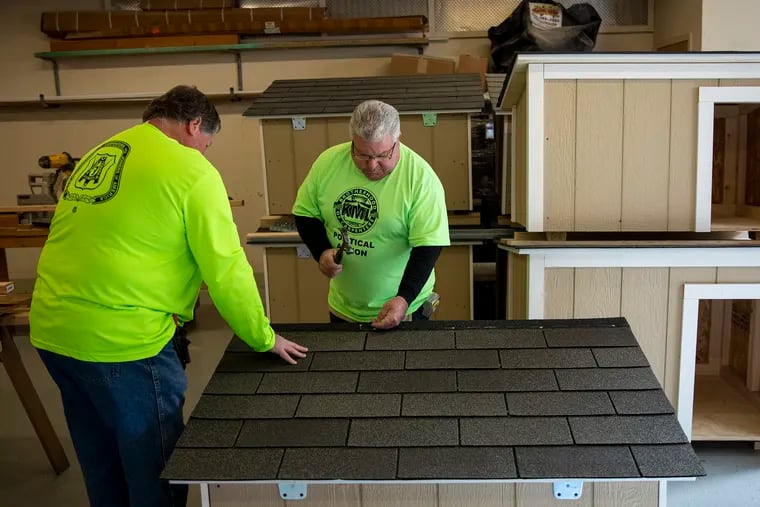Retired union carpenters Ron Socha of Maple Shade, N.J., (left) and Tommy Jordan of Mount Laurel, N.J., finish roofing a doghouse at the Carpenters Union Hall, where they build customized doghouses and donate them to the Pennsylvania SPCA for free distribution to families in need.