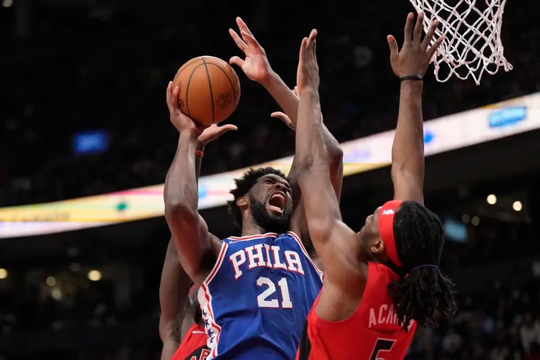 Sixers center Joel Embiid finds tight coverage under the basket from Toronto's Precious Achiuwa.