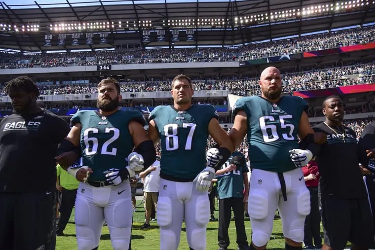 Eagles players Jason Kelce (left), Brent Celek and Lane Johnson hook arms during the playing of the national anthem before a game.
