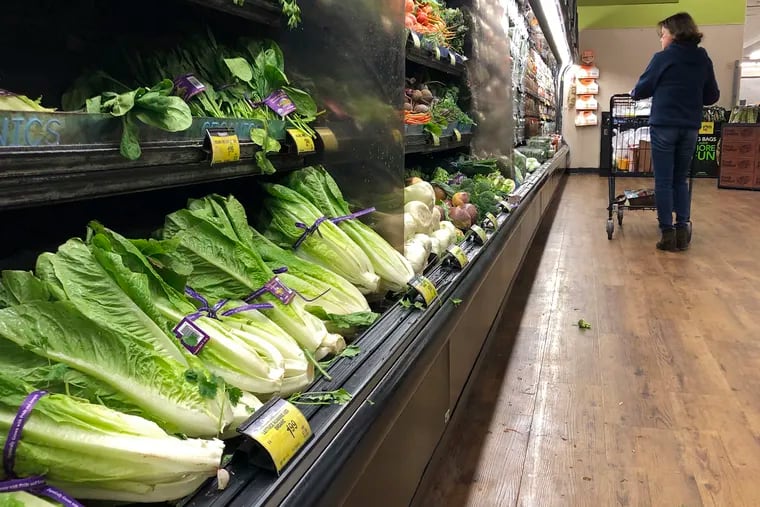 FILE - In this Nov. 20, 2018, file photo, romaine lettuce sits on the shelves as a shopper walks through the produce area of an Albertsons market in Simi Valley, Calif. U.S. health officials have traced a dangerous bacterial outbreak in romaine lettuce to at least one farm in central California. Food regulators said Thursday, Dec. 13, that other farms are likely involved in the E. coli outbreak and consumers should continue checking the label before purchasing romaine lettuce. (AP Photo/Mark J. Terrill, File)