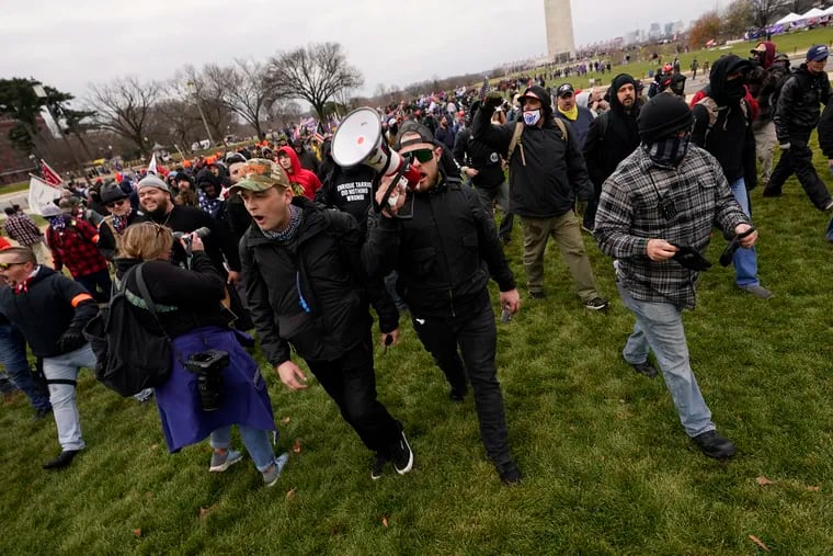 Proud Boys leaders Zach Rehl, of Philadelphia (camouflage hat, left), Ethan Nordean, of Seattle, and Joe Biggs, of Florida, (grey plaid flannel with neck gaiter) lead marchers to the U.S. Capitol on Jan. 6. Nordean and Biggs have both been charged with playing a role in the storming of the Capitol.