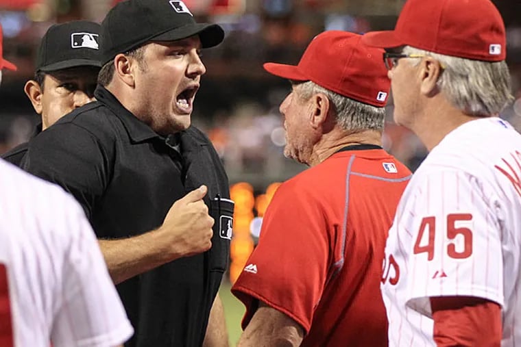 Home plate umpire Dan Bellino throws out Phillies' bench coach Larry Bowa.