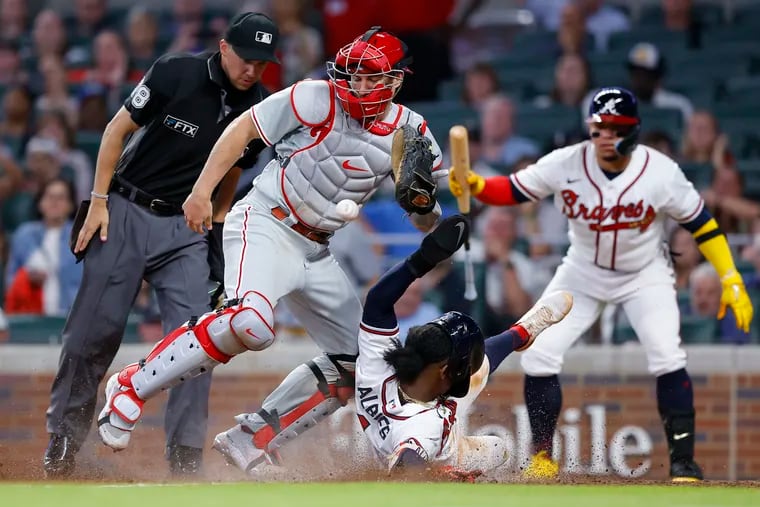 Atlanta Braves Ozzie Albies slides into home to score as the ball gets away from Philadelphia Phillies catcher J.T. Realmuto in the sixth inning of a baseball game, Tuesday, May 24, 2022, in Atlanta. (AP Photo/Todd Kirkland)