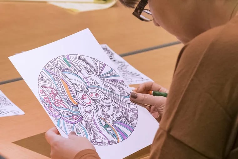 Coloring has become a new past time for adults of all ages. Here, Katie Hardesty, of Voorhees, looks over her work of art created at the at the Cherry Hill library.