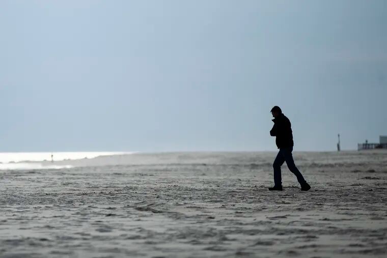 A person walks toward the ocean in Cape May, N.J., Wednesday, March 18, 2020.