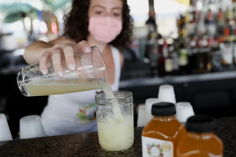 Isabella Abbate, owner of Simply Bella's, demonstrates making a peach vodka lemonade cocktail using her peach simple syrup at her parents' restaurant, Villari's Lakeside, in Sicklerville, N.J., on Thursday, July 30, 2020. Abbate makes a variety of flavored simple syrups.