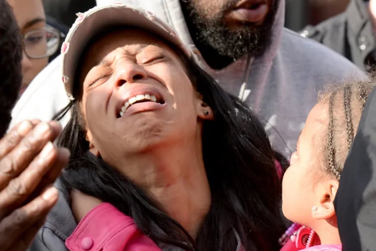 Friends and family comfort Zykia Clavon, whose daughter was killed by a stray bullet, during an antiviolence rally in West Philadelphia.