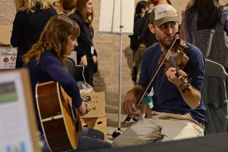 Jen Smith (left) and Nikolai Fox treat patrons to old style bluegrass music at their Temple Fox School of Business Consulting stand.  ( Richard Kauffman / Staff Photographer )