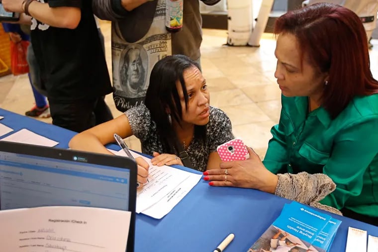 At St. Peter the Apostle Church, Trisayra Ortiz (left) helps Jesofa Milena sign up for insurance.