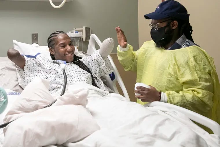 Candice Davis, 30, high-fives her brother, Ali Davis, in her hospital bed at Penn Presbyterian Medical Center in Philadelphia on Tuesday, Nov. 30, 2021. Davis had to have all her limbs partially amputated after a serious bout with COVID-19 in August. Davis has been in high spirits recently, accepting her new reality and journey moving forward.