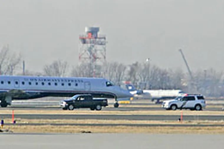 A US Airways Express jet sits on the tarmac at Philadelphia International airport surrounded by police and emergency vehicles, far from the gates, after taking a male passenger off the airplane.