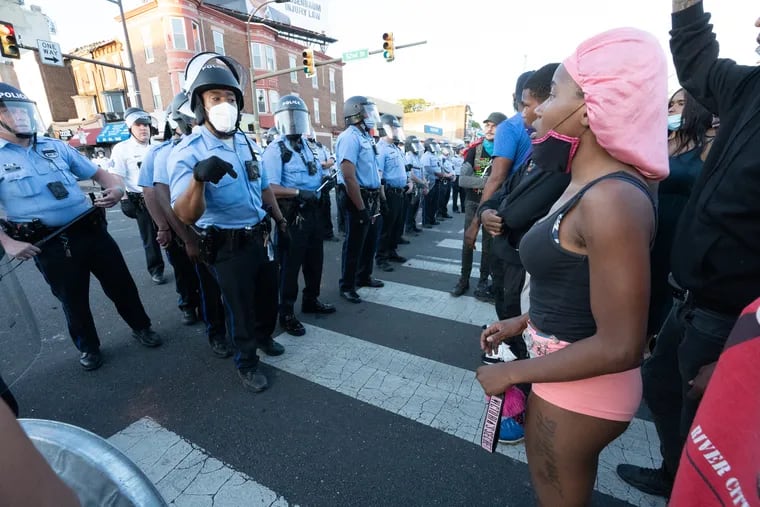 Police talk with people at 52nd and Chestnut Streets, in West Philadelphia, May 31, 2020.