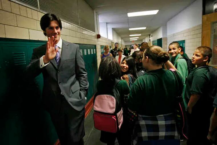 Phillies pitcher Cole Hamels waves in a hallway at Stetson Middle School. The Hamels Foundation donated money to spruce up the school, which Hamels visited with wife, Heidi. &quot;We wanted to give them something to be proud of,&quot; she said.