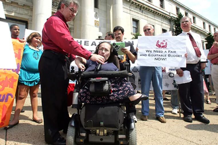 Michael Burke holds a microphone for Ann Cope, head of the Freedom Valley Disability Center, at the rally in Media. (David Swanson / Staff Photographer)
