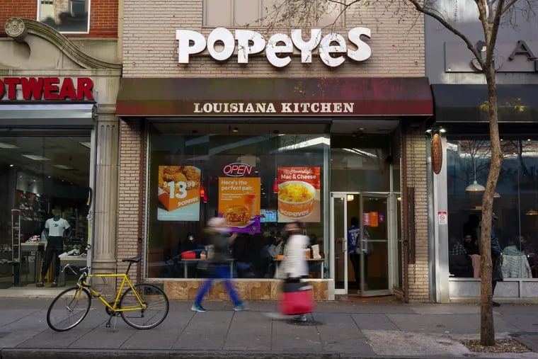 Pedestrians pass the Popeyes Louisiana Kitchen in Center City on Tuesday. This Popeyes posted a sign over the weekend that said homeless people could not enter.