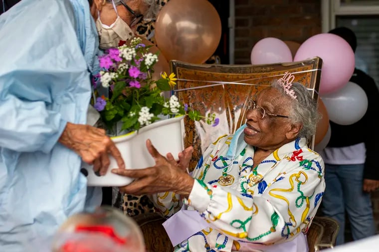 Rena Graves receives a gift from Judy Howard for 100th birthday in Germantown Philadelphia, Pa., on Tuesday Sept. 29, 2020. “To live a life like this, you must live a life in christ,” Graves said. “Live a good clean life, and know who you are and where you’re going. Always have high morals and high standards. Remember to be kind to other people and go out of your way. Just open your heart wherever and whenever is needed. Remember you have time for everything.”