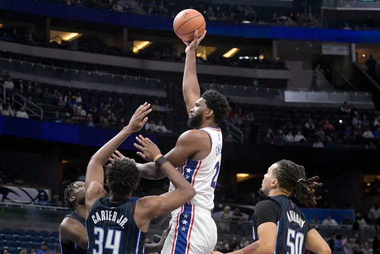Philadelphia 76ers center Joel Embiid (21) goes up for a shot between Orlando Magic center Mo Bamba, left, center Wendell Carter Jr. (34) and guard Cole Anthony (50) during the first half of an NBA basketball game, Wednesday, Jan. 5, 2022, in Orlando, Fla. (AP Photo/Phelan M. Ebenhack)