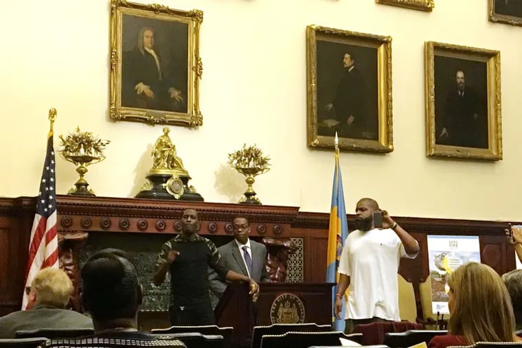 Asa Khalif (left) and Isaac Gardner interrupt a City Hall news conference. At center is Council President Darrell L. Clarke.